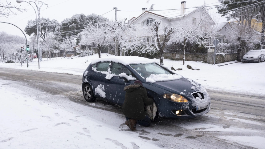 Un hombre pone las fundas a las ruedas de su coche para poder circular en una carretera en Alpedrete, este miércoles, en el que la borrasca Kristin deja nieve en la región de Madrid.