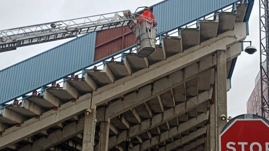 Un operario arregla un desperfecto provocado por el viento en el estadio de fútbol