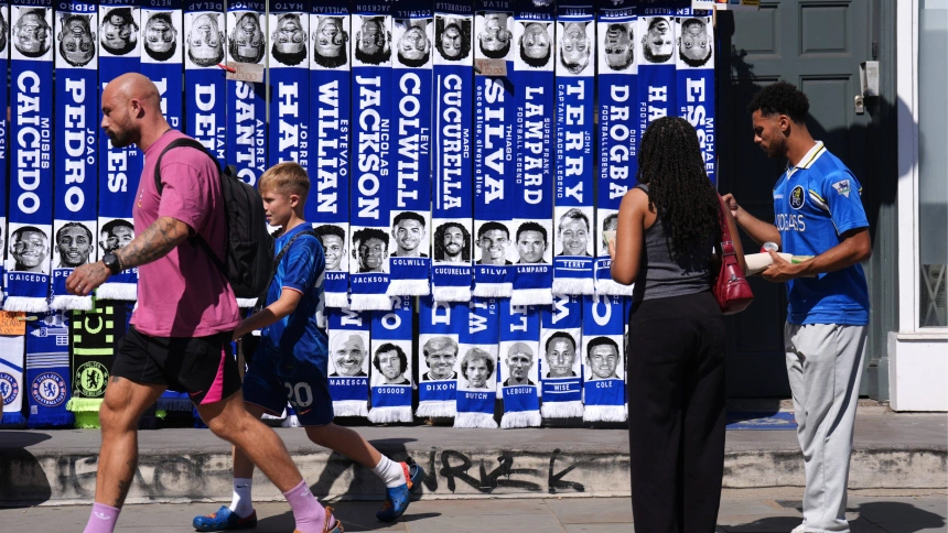 Aficionados del Chelsea pasan junto a un puesto de bufandas en el exterior de Stamford Bridge.