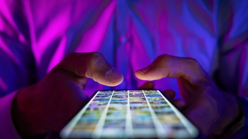 Hombre deslizando el dedo por la pantalla de un teléfono móvil en una habitación