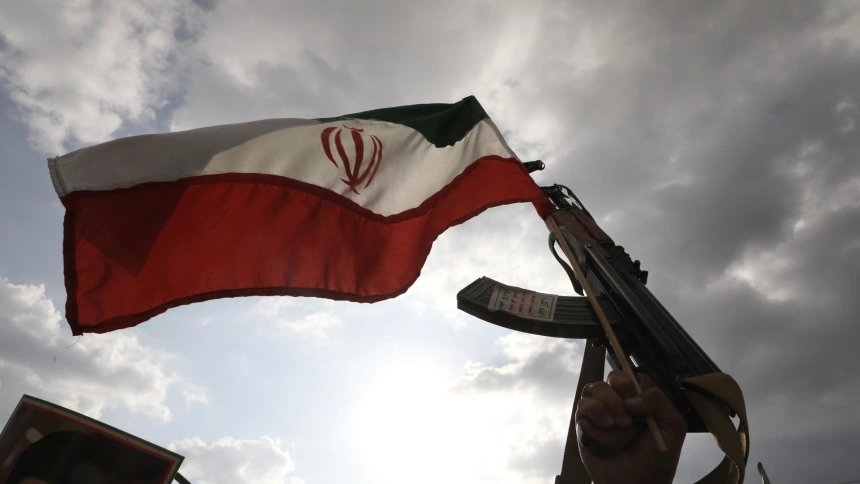 Un partidario hutí sostiene un arma y ondea una bandera iraní durante una protesta contra los ataques estadounidenses e israelíes contra Irán, en Saná, Yemen.