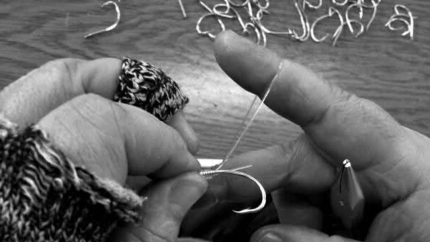 Detalle de las manos ensartando anzuelos en la red