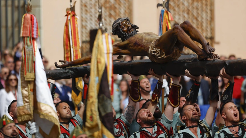 La compañía de honores de la Brigada Rey Alfonso XII de la Legión española porta a hombros el Cristo de la Buena Muerte y Ánimas, conocido como Cristo de Mena, durante el traslado de la imagen este Jueves Santo, en Málaga