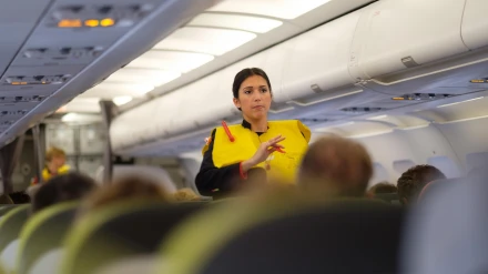 Una azafata de vuelo haciendo la demostración de seguridad con un chaleco salvavidas