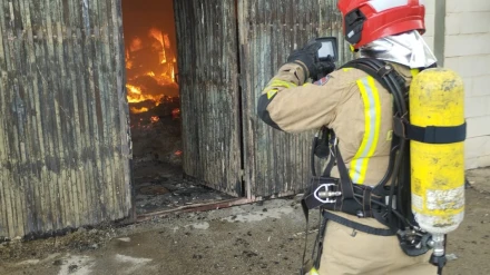 Un bombero trabaja en la extinción del incendio en la nave industrial