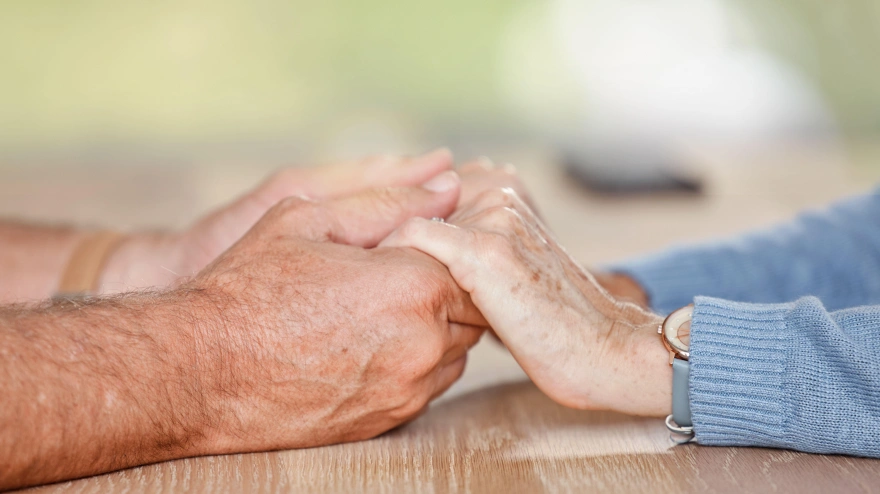 Una pareja de ancianos tomados de la mano en señal de amor, apoyo y confianza durante la jubilación, el asesoramiento y el matrimonio