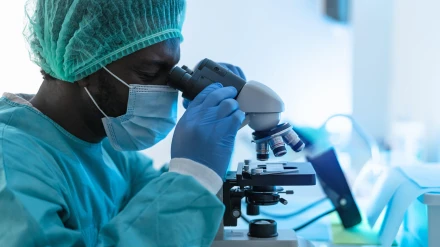 Científico trabajando en laboratorio examinando coronavirus a través del microscopio