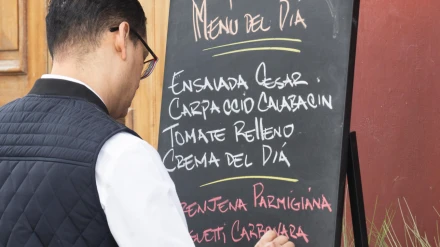 T1F4EM Waiter writing Menu del dia, [menu of the day] on blackboard outside restaurant in Vegueta, Las Palmas, Gran Canaria, Canary Islands, Spain