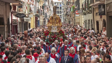 Decenas de personas participan en la procesión en honor a San Fermín, patrón de Pamplona, a 7 de julio de 2023, en Pamplona, Navarra (España).  Miles de pamploneses ataviados de blanco y rojo han salido a las calles de Pamplona hoy, día grande de las fiestas de San Fermín, para arropar al santo en su recorrido por el Casco Antiguo de la ciudad. La figura de San Fermín ha estado arropada por la Comparsa de Gigantes y cabezudos, las cruces parroquiales, la Cruz Arzobispal, los gremios y cofradías, dantzaris municipales, txistularis, clarinero y timbales, el cabildo Catedralicio Arzobispo de Pamplona, la bandera de la ciudad, maceros, libreas, la Corporación municipal, Policía Municipal, escolta de gala y La Pamplonesa. Las fiestas en honor a San Fermín, comenzaron ayer, 6 de julio con el tradicional chupinazo y se prolongan hasta el 14 de julio con el cántico del ‘Pobre de mí’. Un año más, la calle es el escenario principal de las fiestas de San Fermín, fechas en las que se han programado 542 actos oficiales, 300 de ellos de carácter musical. Esta fiesta que atrae a millones de visitantes cada año por su ambiente festivo y sus populares encierros, está declarada de Interés Turístico Internacional.