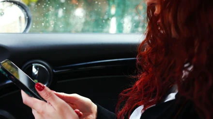 Chica con teléfono inteligente en la carretera durante un viaje en coche