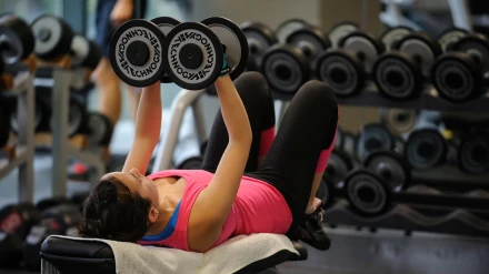 Una mujer entrenando pesas en el gimnasio