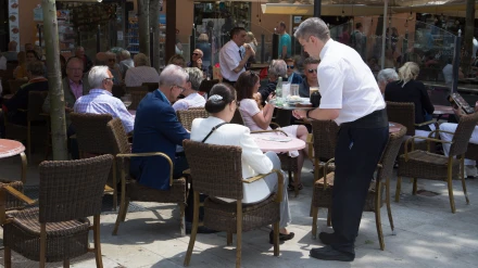 Un camarero atiende a una clienta en España