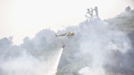 Un helicóptero tira agua sobre una zona de incendio, imagen de archivo