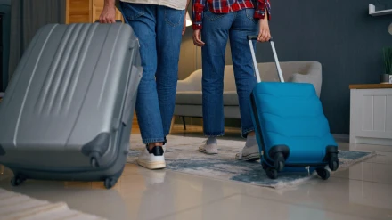 Pareja saliendo de casa con las maletas