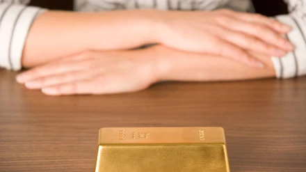 Mujer mirando un lingote de oro. Archivo