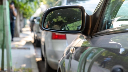 Espejo retrovisor de un automóvil estacionado cerca de la acera al costado de la calle