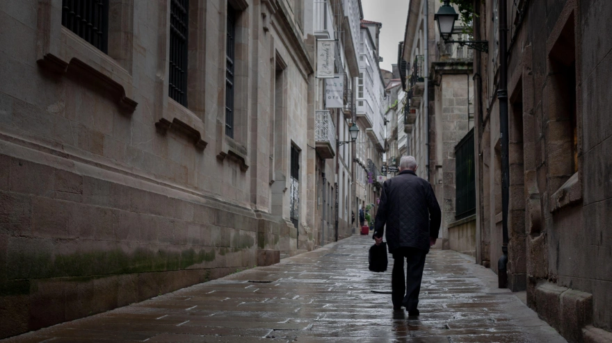 Un anciano solitario camina por una calle del casco antiguo de Santiago de Compostela
