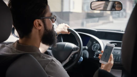 Hombre consulta móvil al volante