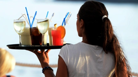 Camarera llevando una bandeja con bebidas, imagen de archivo