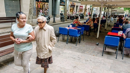 Jubiladas pasan por delante de una terraza de Barcelona