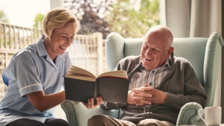 Una persona leyendo un libro junto a la persona que cuida