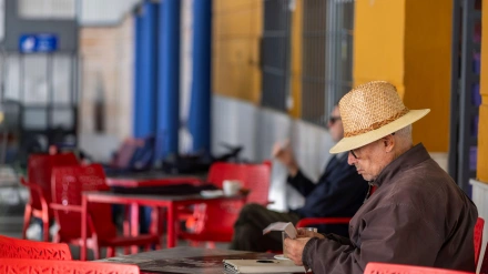 Un jubilado con sombrero de paja relajándose en una cafetería de Ronda