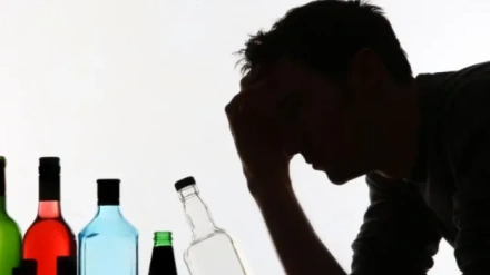 La sombra de una persona frente a botellas de alcohol