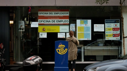 Mujer frente a una oficina de empleo (SEPE) leyendo los carteles expuestos en el escaparate en Madrid