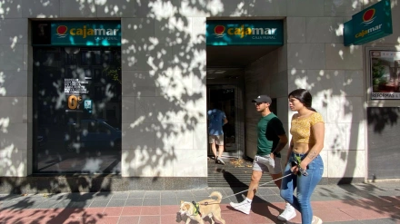 Dos personas pasan por delante de una oficina de Cajamar