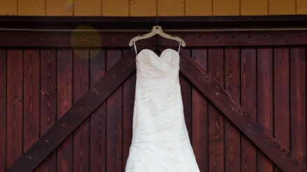Vestido de novia blanco colgado en grandes puertas teñidas de granate.