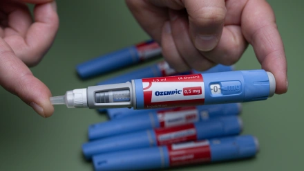 Una mano que sostiene una jeringuilla de inyección de Ozempic (0,5 mg), con otras jeringuilla en el fondo, simboliza el control de la diabetes