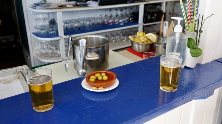 Dos vasos de cerveza y aceitunas en el mostrador de un bar de playa.