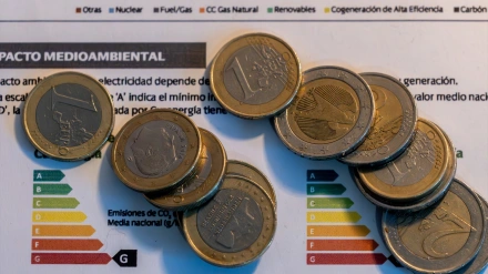 Varias monedas sobre una factura de la luz
