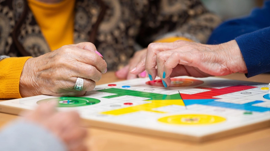 Grupo de jubiladas jugando al clásico juego de parchís en una residencia de ancianos