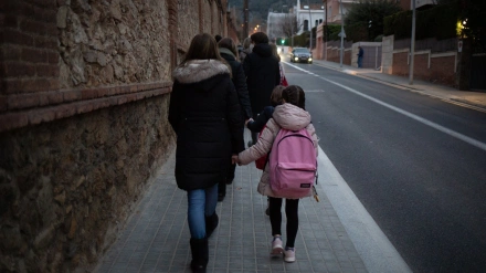 Una mujer lleva de la mano a un niño a la clase