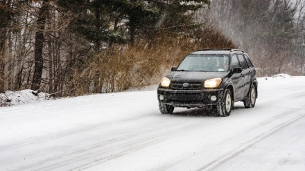 M529GX Black SUV driving on rural road in heavy snow fall.