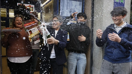 Varias personas celebran a las puertas de la administración de loterías del número 10 de la calle Barquillo
