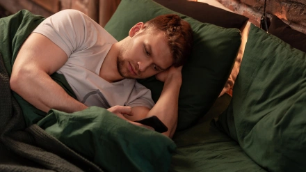 Hombre de negocios barbudo acostado en la cama y navegando por las redes sociales