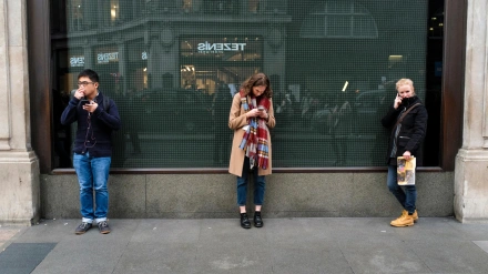 HP8APY Three young people using mobile phones in street