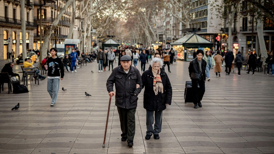Una pareja de jubilados camina por la Rambla de Barcelona.