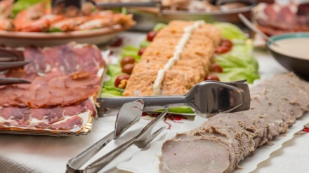 Bandejas con diferentes platos de comida, carnes, embutidos, pastel de pescado, mariscos de fondo, todo preparado para una gran comida navideña.
