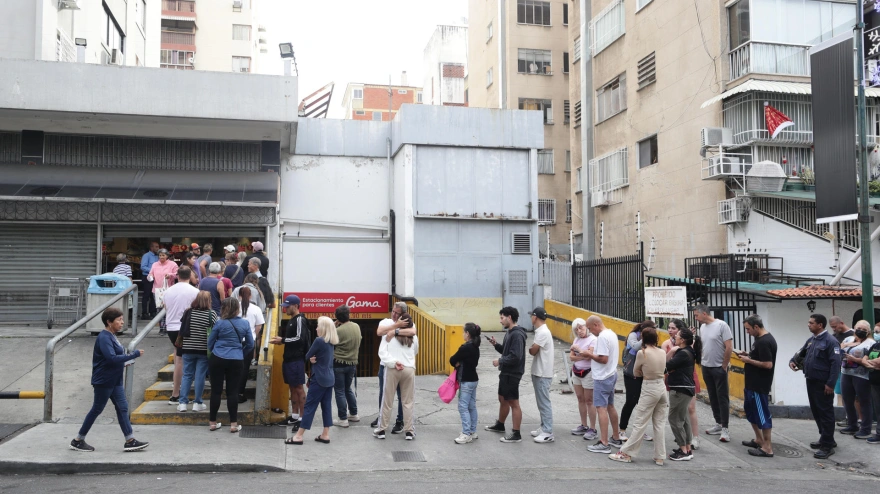 Personas hacen fila en un supermercado para abastecerse este sábado en Caracas