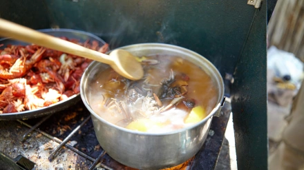 Cocinar marisco variado en un pequeño hornillo de gas portátil con cangrejos hervidos