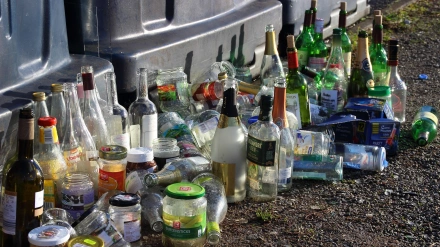 Botellas y frascos de vidrio junto a un contenedor