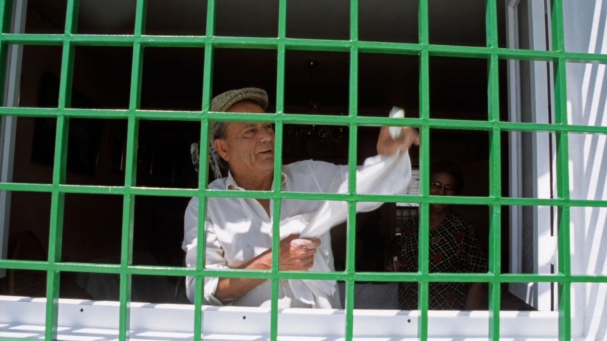 Un jubilado limpiando una ventana en Frigiliana