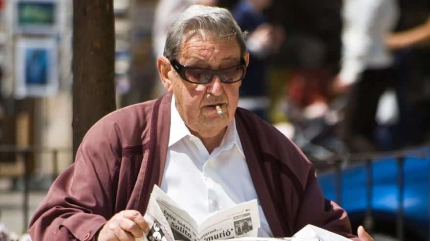 Jubilado leyendo un periódico en un banco del parque, Valencia