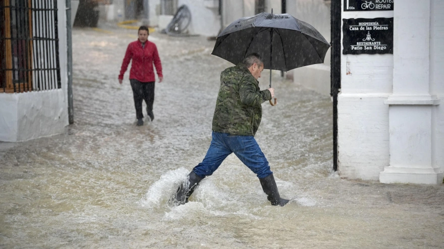 Vecinos de Grazalema (Cádiz) caminan por una calle inundada debido a las intensas lluvias