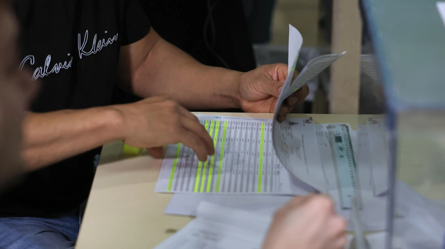 Un miembro de una mesa electoral revisa el censo de votantes en un colegio electoral este domingo en Zaragoza