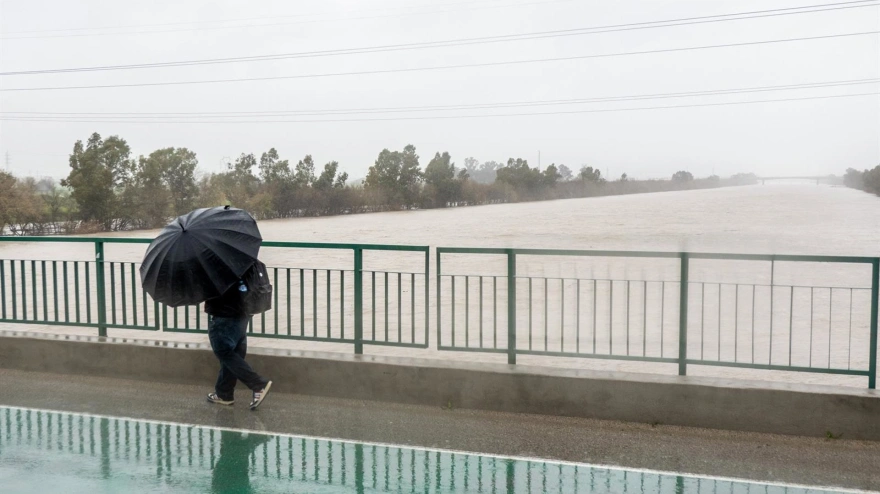 Una persona cruza por el Puente de la Señorita cortado al tráfico por el desbordamiento parcial del río Guadalquivir a su paso por la Cartuja