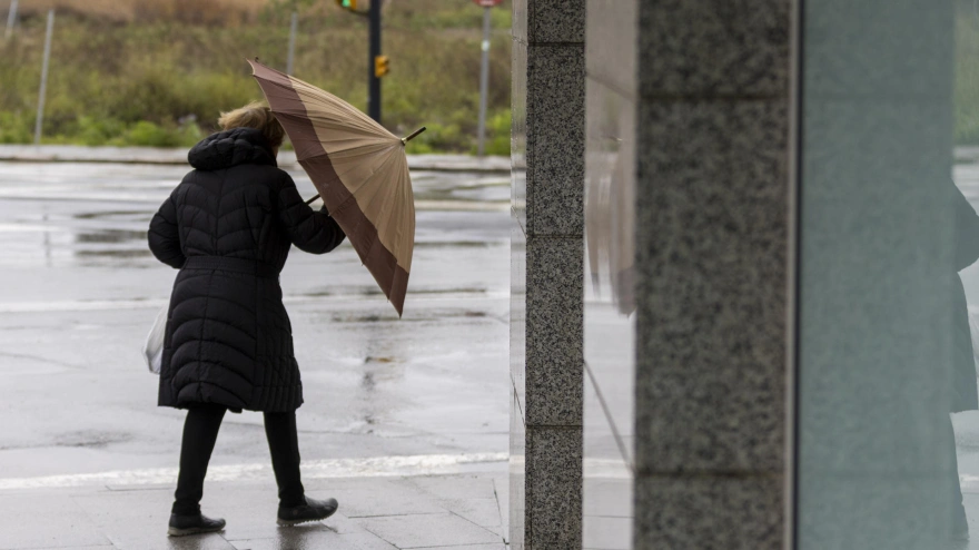 Una mujer se protege del viento y la lluvia en Huelva